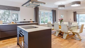 Une cuisine moderne dotée d’un îlot central, d’un coin repas avec des chaises et de grandes fenêtres.