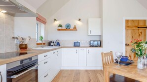 Een keuken met witte kastjes, een houten aanrecht, een magnetron en een spoelbak.