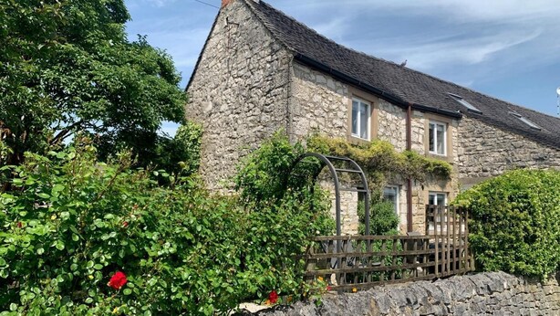 A stone house with a tiled roof, a wooden fence, and a stone wall. - 4 Bed in Matlock (oc-85450) (Brassington)