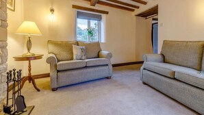 A cozy living room with two sofas, a lamp, a window with a view, and a stone wall. - 4 Bed in Matlock (oc-85450) (Brassington)
