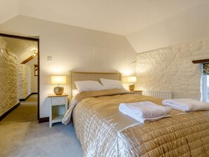 A bedroom with a stone wall, a wooden headboard, a bed with a quilt, bedside lamps, and a radiator. - 4 Bed in Matlock (oc-85450) (Brassington)