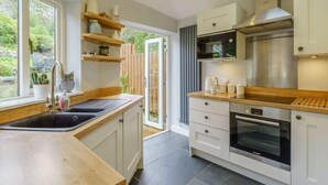 Een moderne keuken met een groot raam, een ingebouwde oven en houten aanrechtbladen.