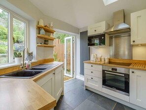 Eine moderne Küche mit großem Fenster, integriertem Backofen und Holzarbeitsplatten.