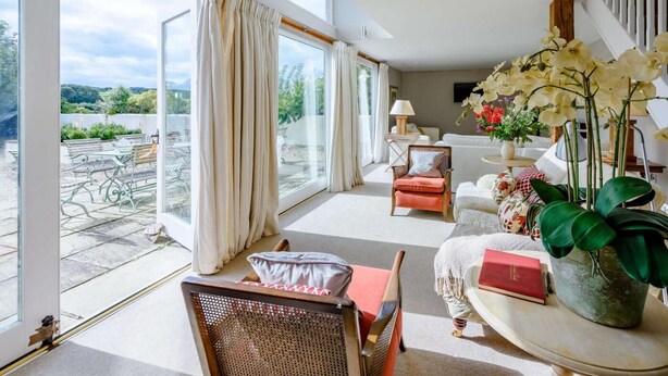 Um quarto espaçoso com amplas janelas, área de jantar e espaço de estar com vista para o exterior.