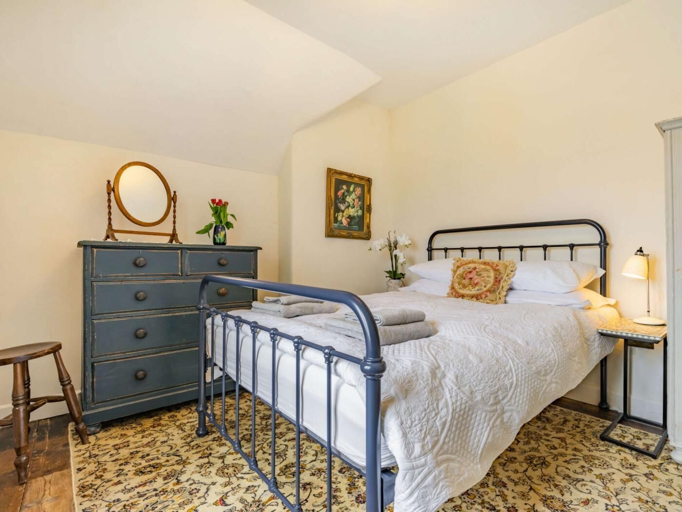 Un dormitorio con cama, cómoda, espejo y un cuadro en la pared.