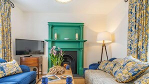 A living room with a green fireplace, blue sofas, a wooden coffee table, and a television. - 3 Bed in Whitby (oc-85927) (Fylingdales)