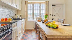 A kitchen with a checkered floor, a stove, a sink, and a window with curtains. - 3 Bed in Whitby (oc-85927) (Fylingdales)