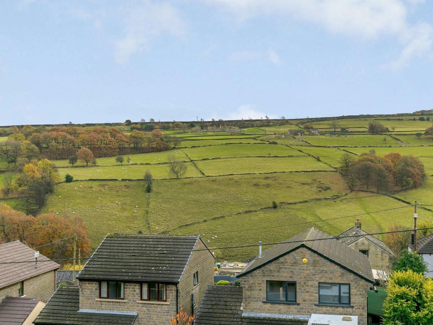 A rural landscape with stone houses, green fields, and a clear sky.