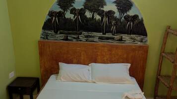A bed with a headboard featuring a painted landscape, a small wooden nightstand, and a ladder against the wall.