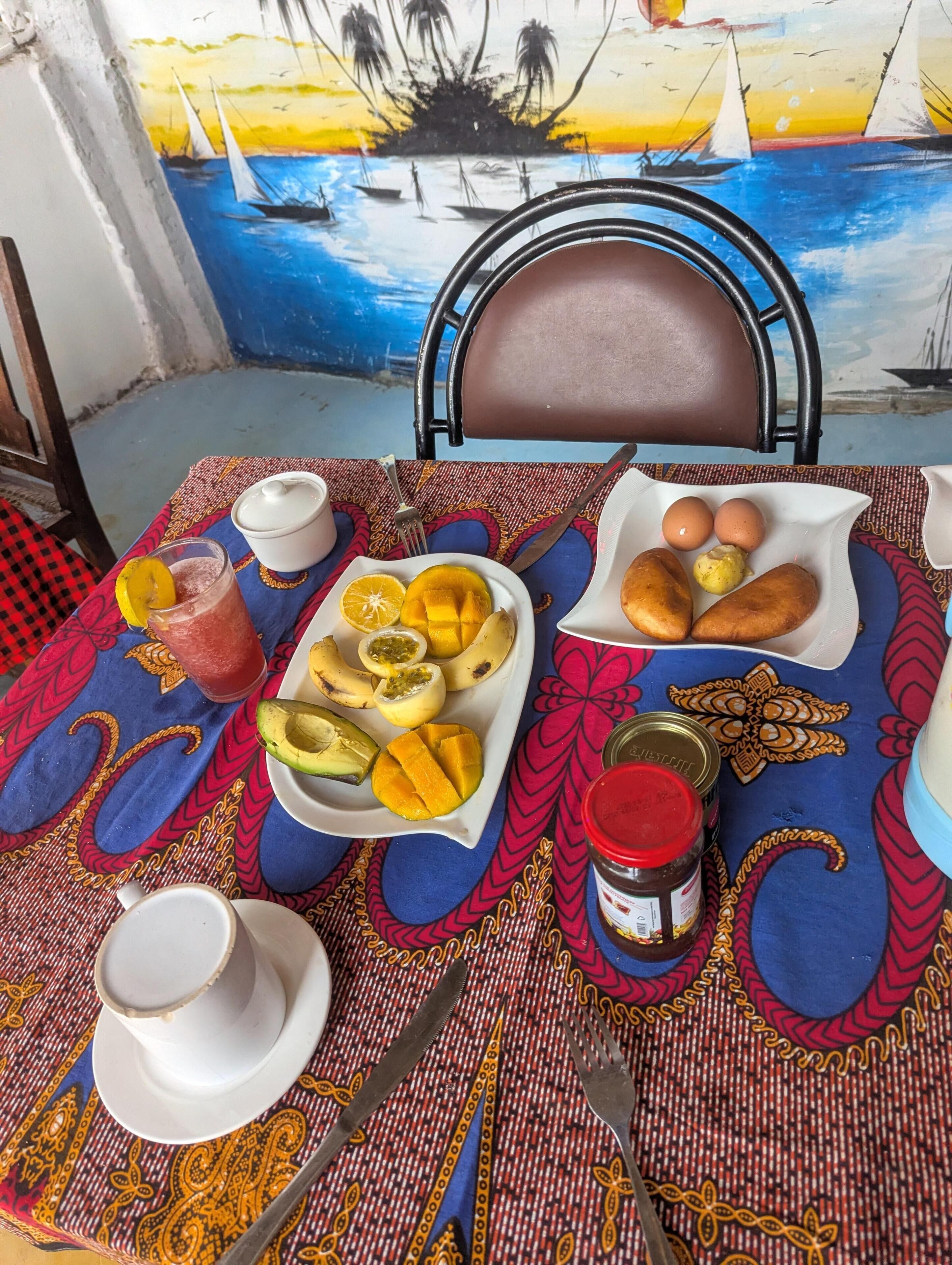 A table set with a meal, including a fruit bowl, bread, eggs, and condiments.
