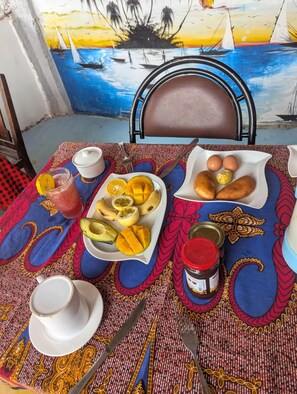 A table set with a meal, including a fruit bowl, bread, eggs, and condiments.