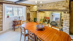 A dining room with a stone wall, wooden table, and chairs. - 4 Bed in Oakham (oc-86556) (Empingham)