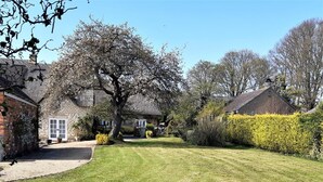 A residential property with a well-maintained lawn, a large tree, and a brick house with a white door. - 4 Bed in Oakham (oc-86556) (Empingham)