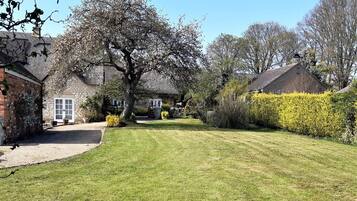 A residential property with a well-maintained lawn, a large tree, and a brick house with a white door.