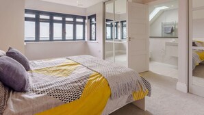 Un dormitorio con cama, ventana, puerta y vista al baño.