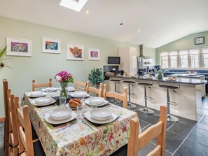Un coin repas avec une table dressée pour six personnes, entourée de chaises en bois.
