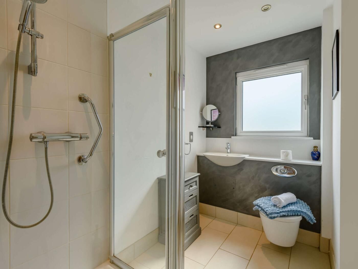 Une salle de bain avec une douche à parois de verre, un lavabo avec un miroir et des toilettes.
