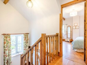 Een houten trap die leidt naar een slaapkamer met een bed, een spiegel en ingelijste foto's aan de wand.