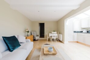 Ein modernes Wohnzimmer mit einer Couch, einem Couchtisch mit Tablett und einem Essbereich mit Tisch und Stühlen.