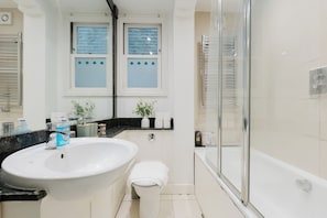 A modern bathroom with a large sink, toilet, and glass shower enclosure. - Chic 2BDR Retreat in Wandsworth Town (Greater London)