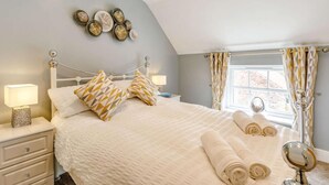 A bedroom with a bed, pillows, a bedside table, a lamp, a mirror, and a window with curtains. - 3 Bed in Bedale (oc-88242) (Snape)