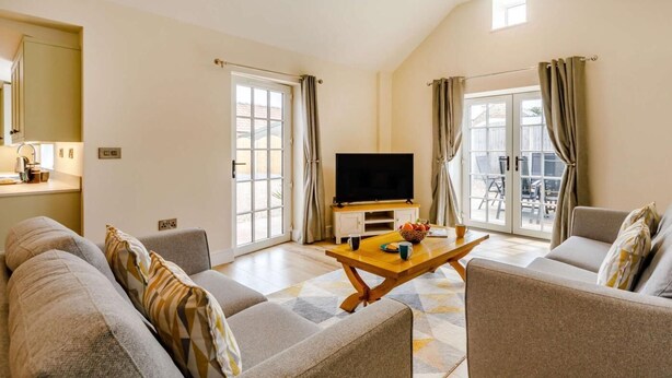 A living room with a sofa, armchair, coffee table, TV, and a balcony view. - 3 Bed in Bedale (oc-88242) (Snape)