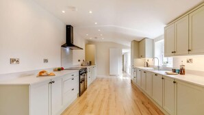 A modern kitchen with white cabinetry, a central island, and a view into the adjacent dining area. - 3 Bed in Bedale (oc-88242) (Snape)