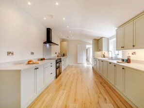 A modern kitchen with white cabinetry, a central island, and a view into the adjacent dining area. - 3 Bed in Bedale (oc-88242) (Snape)