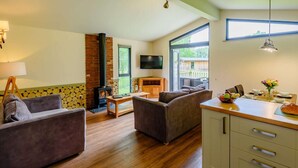 Una sala de estar con chimenea, televisor y comedor con mesa lista para dos.