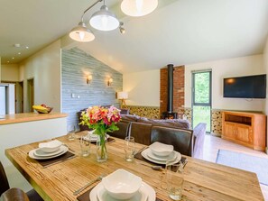 A dining area with a wooden table set for four, a vase of flowers, and a fireplace in the background. - 2 Bed in Newark (oc-88427) (Perlethorpe)
