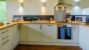 Una cocina moderna con horno empotrado, microondas y campana extractora de acero inoxidable.