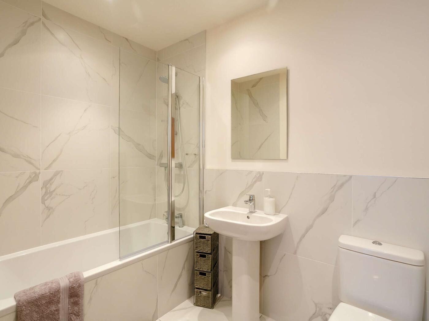 Ein Badezimmer mit Duschkabine, Standwaschbecken und Toilette.