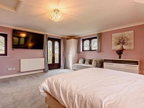 Ein Schlafzimmer mit Bett, Fernseher, Heizkörper, Fenster und Tür.