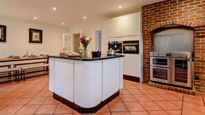 A modern kitchen with a central island, built-in ovens, and a brick fireplace. - 5 Bed in Southampton (oc-89078) (Burridge)