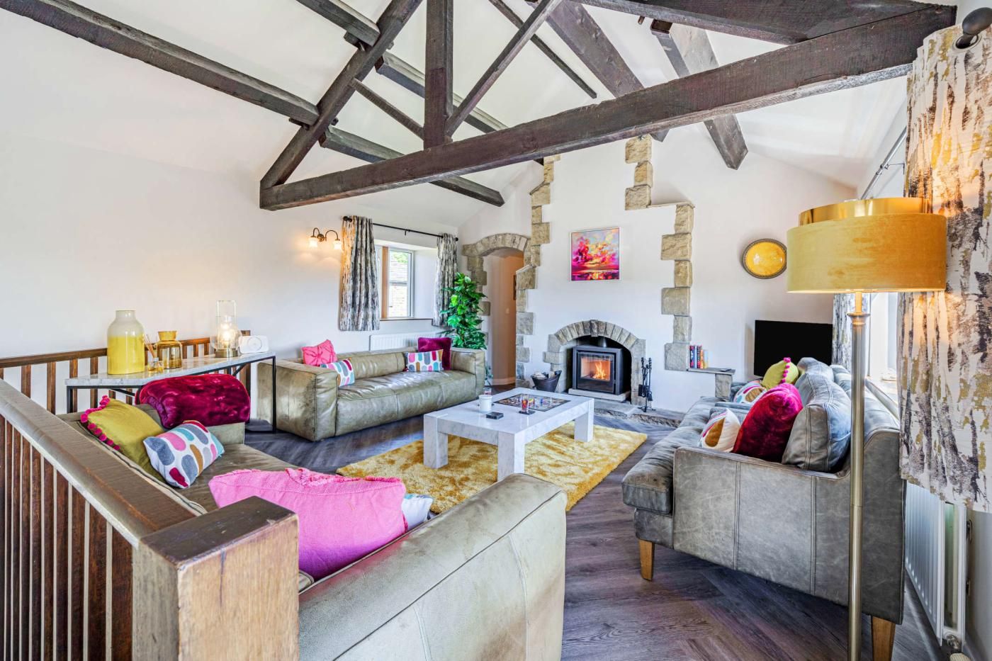 A cozy living room with a fireplace, wooden beams, and comfortable seating.