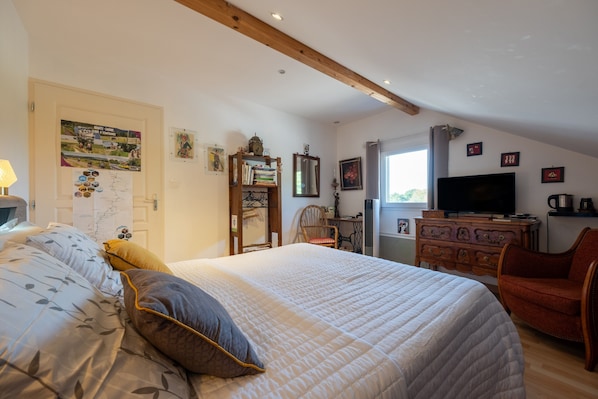 Un dormitorio con una cama grande, un aparador de madera, un televisor y una silla.