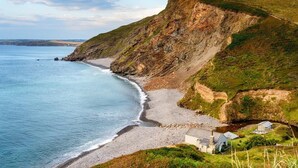 A coastal landscape with a beach, cliffs, and a small building. - 6 Bed in Holsworthy (oc-89218) (Holsworthy Hamlets)