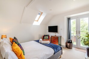 Une chambre à coucher avec un lit, une commode, un téléviseur et une fenêtre de toit.