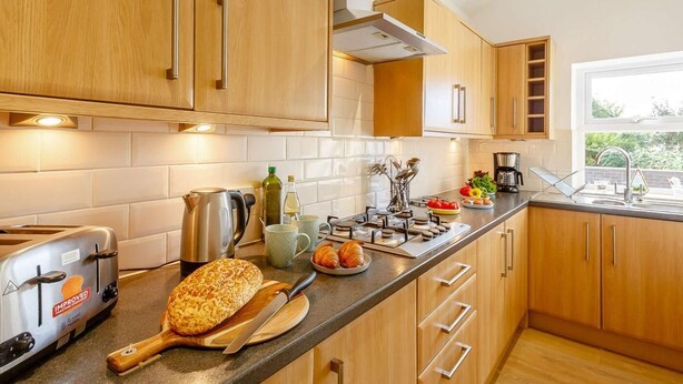 Una cocina moderna con armarios de madera, horno empotrado y ventana que proporciona luz natural.