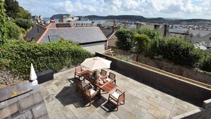 Un patio en la azotea con una mesa y sillas, un muro de ladrillo y vistas de la ciudad.