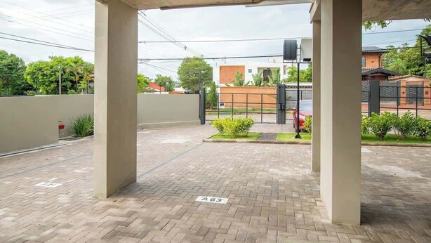 Un espace extérieur abrité, doté d’un sol pavé, d’une porte et d’un bâtiment en arrière-plan.