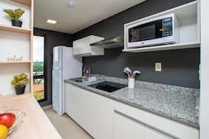 Una cocina moderna con microondas, pileta y muebles blancos.