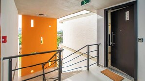 L’entrée d’un hôtel, avec un escalier, une porte portant l’inscription « A63 » et un mur d’un orange vif.