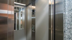 Un moderno ascensor con puertas de acero inoxidable y una pantalla digital.
