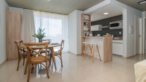 Un appartement moderne comprenant un coin repas, une cuisine et une grande fenêtre avec des rideaux.