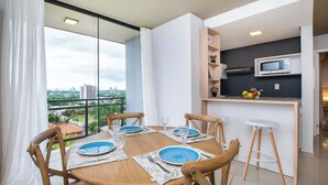 Un comedor con una mesa dispuesta para cuatro, una cocina con microondas y vistas a la ciudad.