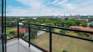 Un balcon offrant une vue sur le paysage urbain, avec ses bâtiments et sa végétation.