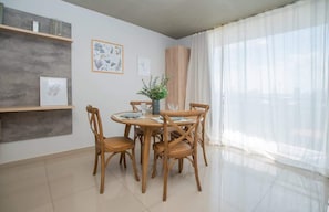 A dining area with a round table, four wooden chairs, a vase with greenery, and framed botanical prints on the wall. - Corporate Stays Insignia 4 - A63 (Lúke)