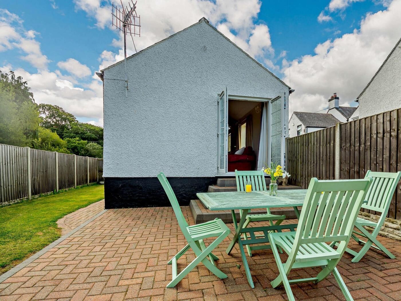 A small house with a patio, a table with chairs, and a wooden fence.