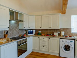 A kitchen with white cabinets, a microwave, a stove, a dishwasher, and a washing machine. - 2 Bed in Abergele (oc-89413) (Betws-yn-Rhos)